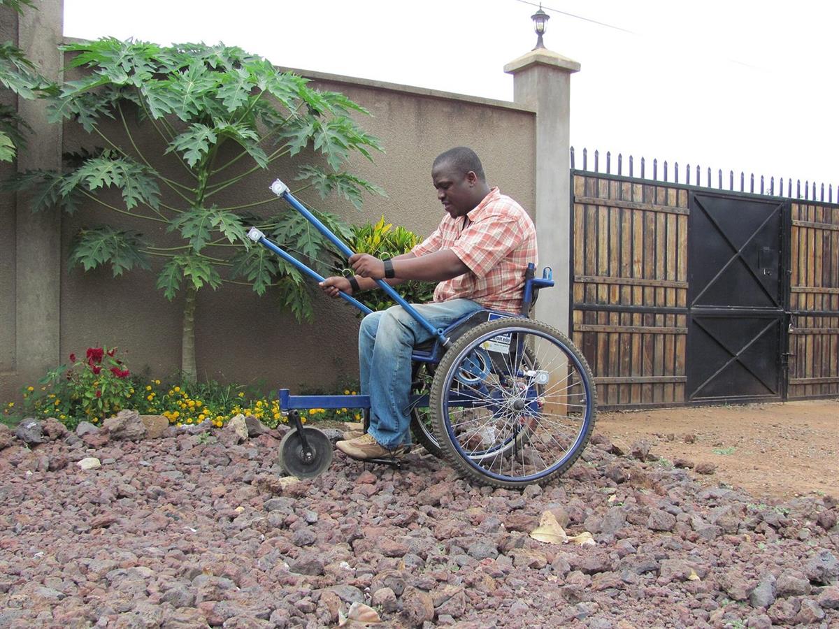 A man travelling by hand-cranked wheelchair along a street