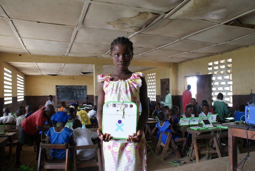 A girl standing with a laptop in her classroom